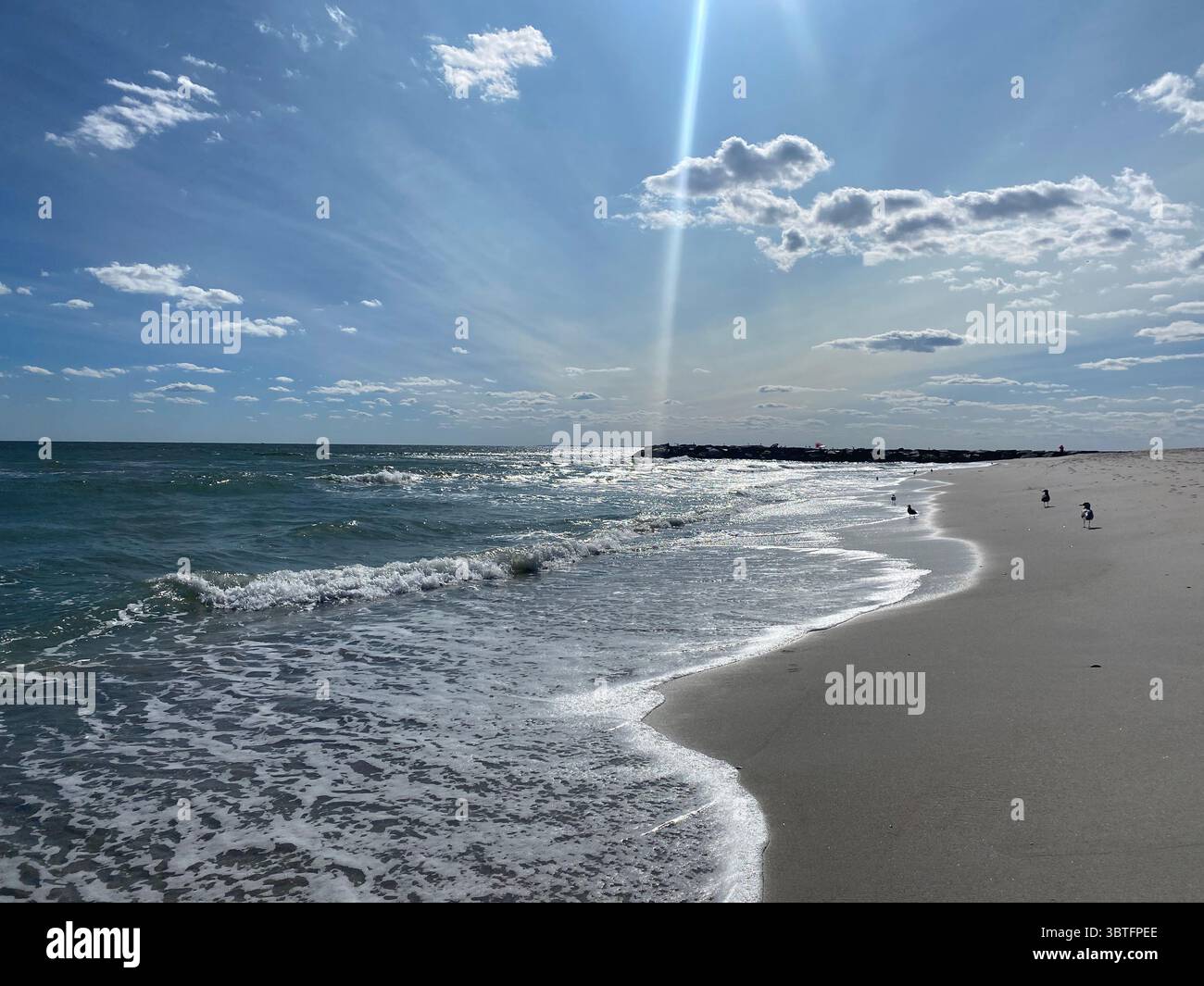 Strand mit Wolken und Sonnenlicht - Smartphone-aufgenommenes Stockfoto