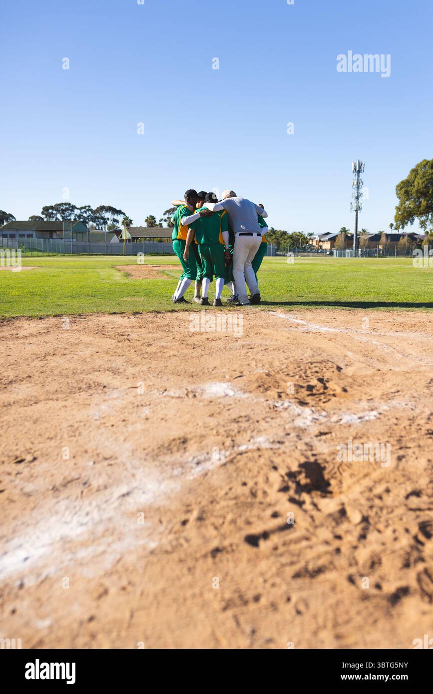 Verschiedene männliche Baseballteams drängen sich auf Pitcher Mound und tragen grüne und gelbe Trikots Stockfoto