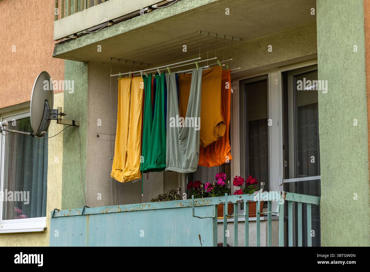 Bunte Hosen, lange Winterhosen, hängend auf dem Balkon eines Mehrfamiliengebäudes, Wäschetrocknung am Bahnhof Stockfoto