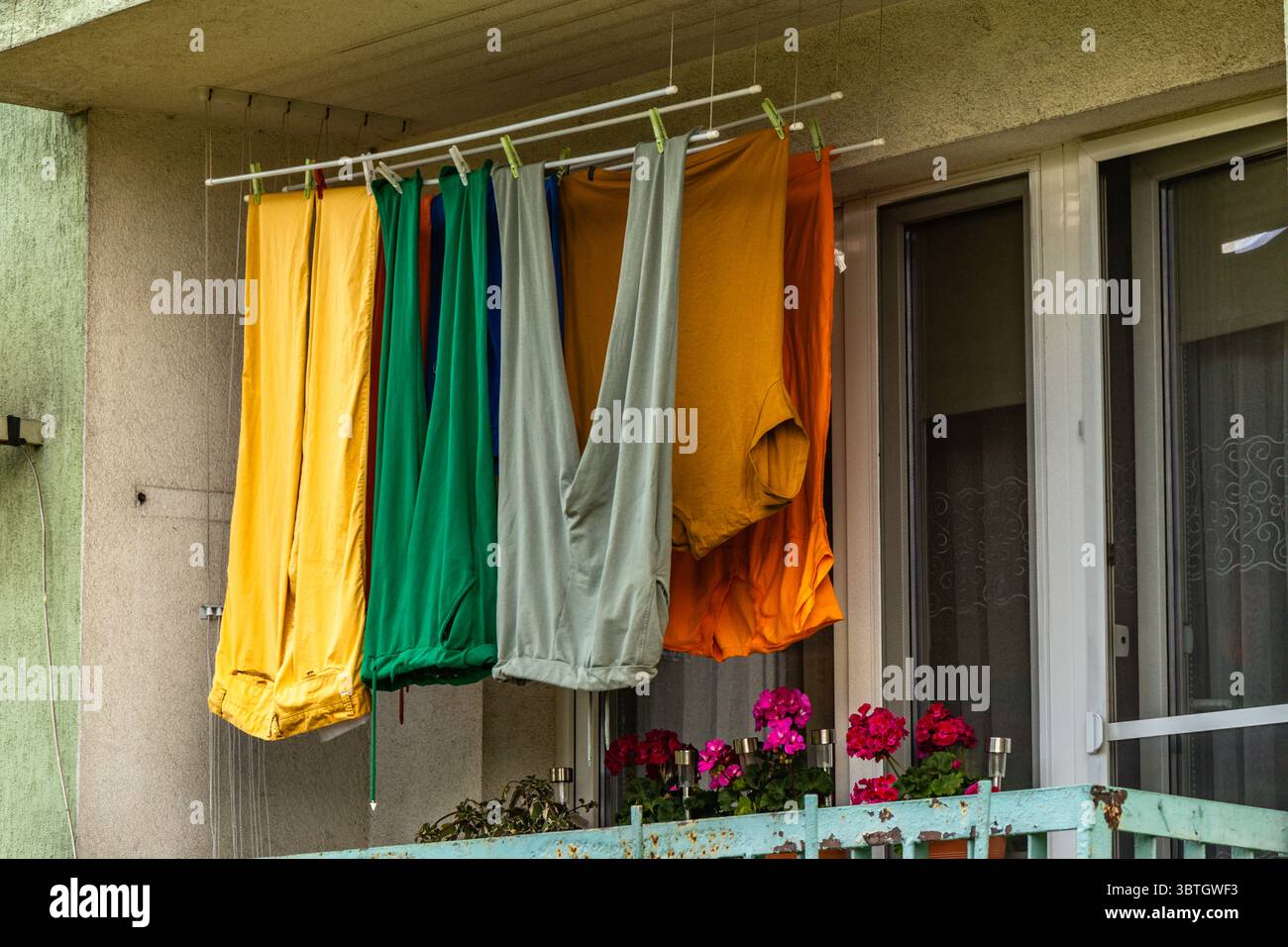 Bunte Hosen, lange Winterhosen, hängend auf dem Balkon eines Mehrfamiliengebäudes, Wäschetrocknung am Bahnhof Stockfoto