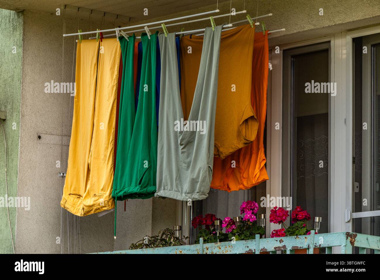 Bunte Hosen, lange Winterhosen, hängend auf dem Balkon eines Mehrfamiliengebäudes, Wäschetrocknung am Bahnhof Stockfoto