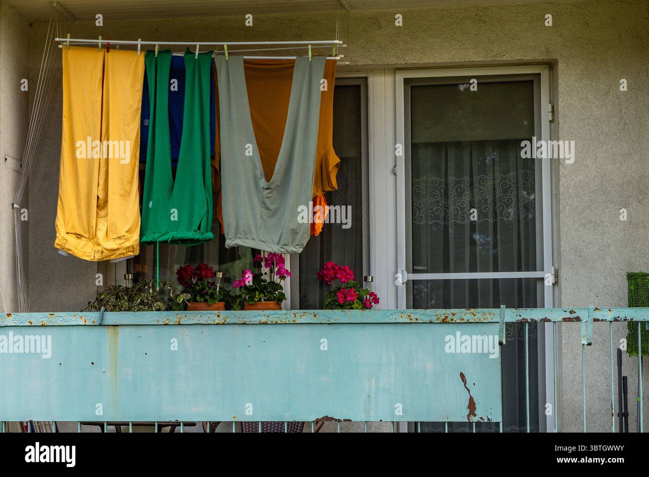Bunte Hosen, lange Winterhosen, hängend auf dem Balkon eines Mehrfamiliengebäudes, Wäschetrocknung am Bahnhof Stockfoto