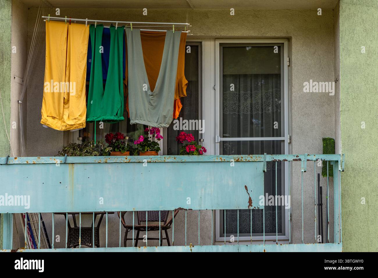Bunte Hosen, lange Winterhosen, hängend auf dem Balkon eines Mehrfamiliengebäudes, Wäschetrocknung am Bahnhof Stockfoto