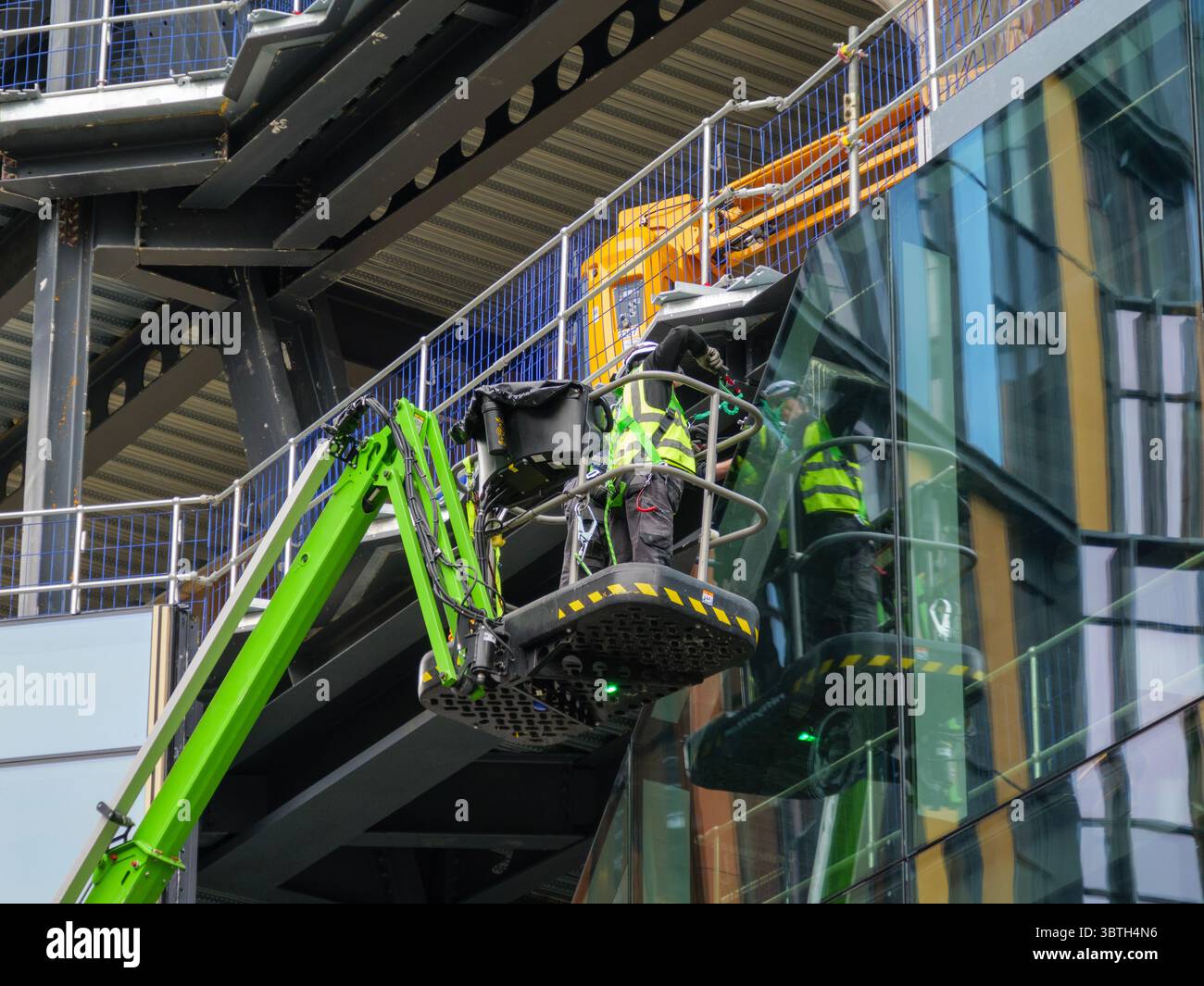 Bauarbeiter betreiben einen Kirschpflücker, um Fassadenpaneele an der 2 Finsbury Avenue, einem Hochhaus in Broadgate, City of London, zu installieren – Teil eines großen Stadterneuerungsprojekts im britischen Finanzviertel. Stockfoto