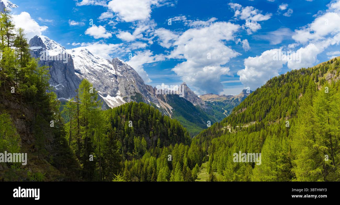 Ein atemberaubender Panoramablick auf die Dolomiten, mit den schneebedeckten Gipfeln der Marmolada auf der linken Seite, üppig grünen Tälern und einem leuchtend blauen Himmel mit Scatter Stockfoto