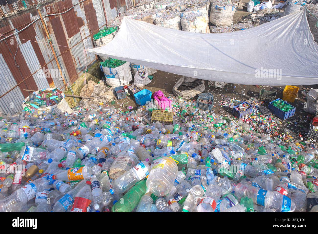 15. Juli 2025, Chittagong, Chittagong, Bangladesch: Arbeiter sortieren in einer Recyclingfabrik in Chittagong gebrauchte Plastikflaschen. Diese Kunststoffflaschen, die häufig zur Verpackung von Trinkwasser verwendet werden, benötigen sehr lange, bis sie vollständig zersetzt sind. Wenn sie verbrannt werden, geben sie giftige Dämpfe in die Umwelt ab. Schwimmende Kunststoffabfälle können viele Jahre im Wasser überleben und dienen oft als winzige Fahrzeuge für invasive Arten, die natürliche Lebensräume bedrohen. Tief im Boden vergraben, können Kunststoffe schädliche Chemikalien freisetzen, die in das Grundwasser gelangen und ernsthafte Risiken für die Umwelt darstellen Stockfoto