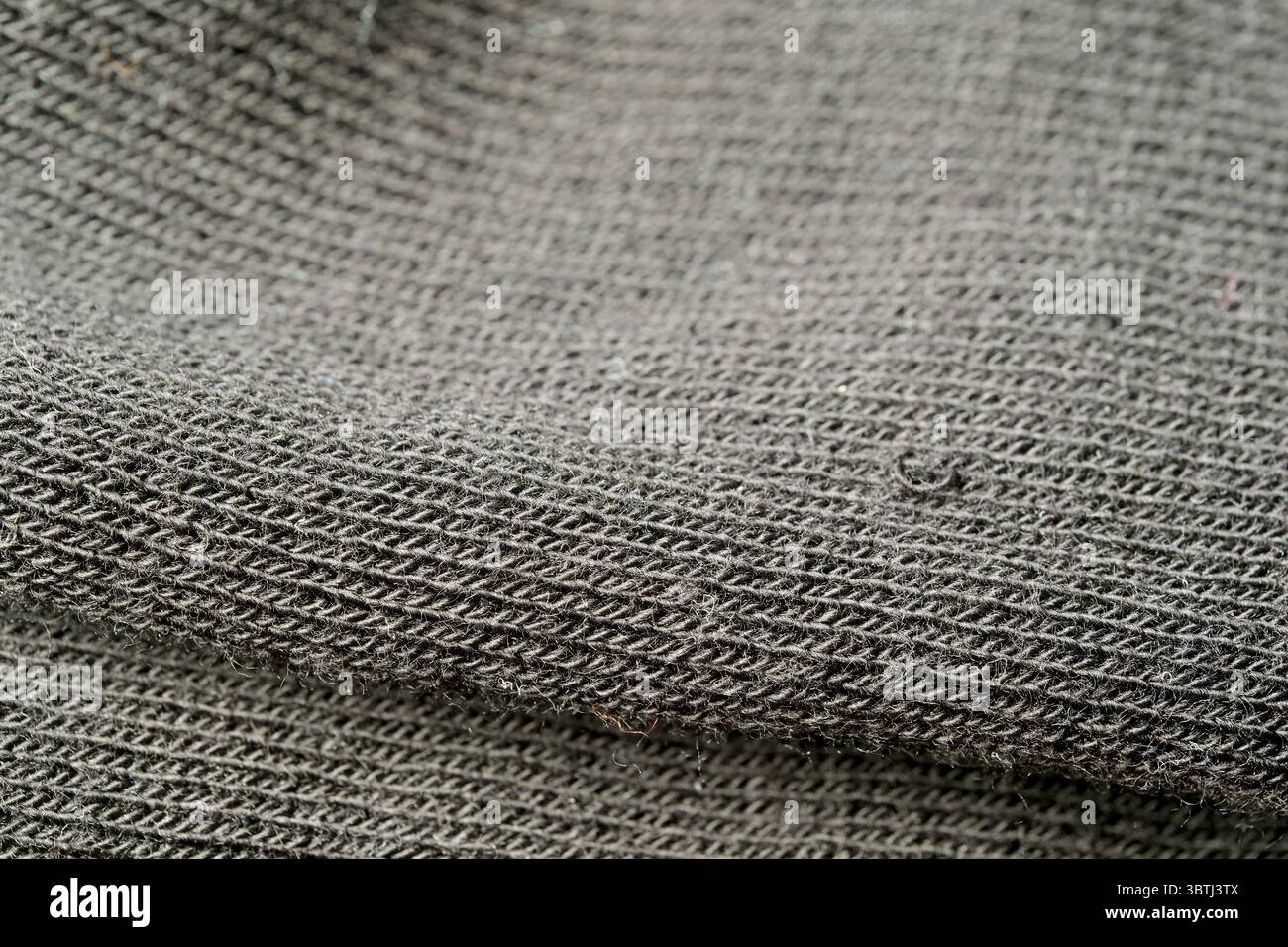 Nahaufnahme eines gewebten Textils mit komplizierten Mustern und sanften Grautönen. Stockfoto