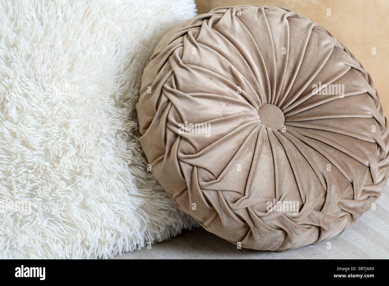 Weiche Kissen in Beige und Creme sorgen für Wärme in einem schicken Loungebereich. Stockfoto