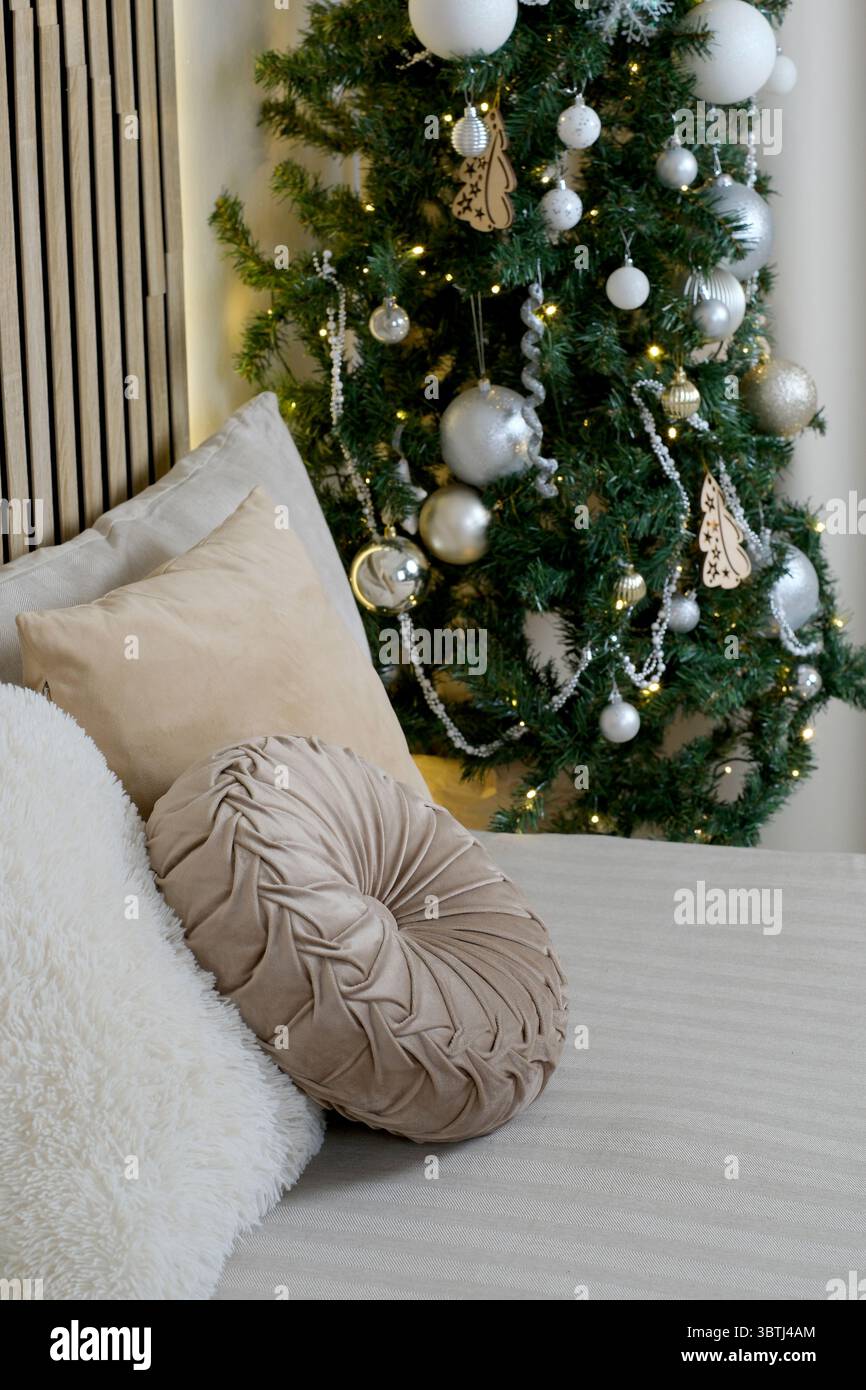 Weiche Kissen gegen einen wunderschön geschmückten Weihnachtsbaum. Stockfoto