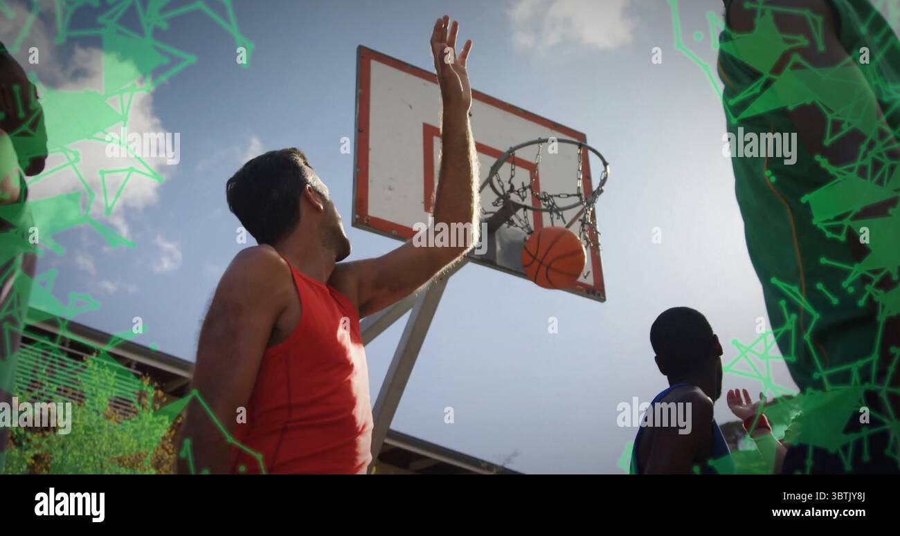 Springender Mann in rotem Panzertop, der auf dem Basketballfeld im Freien einen Korb erreicht, mit Basketball durch das Netz Stockfoto