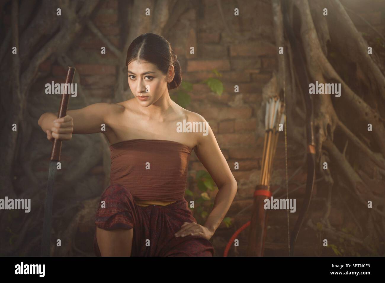 Porträt einer Frau in traditioneller thailändischer Kleidung, die ein Schwert hält, Thailand Stockfoto