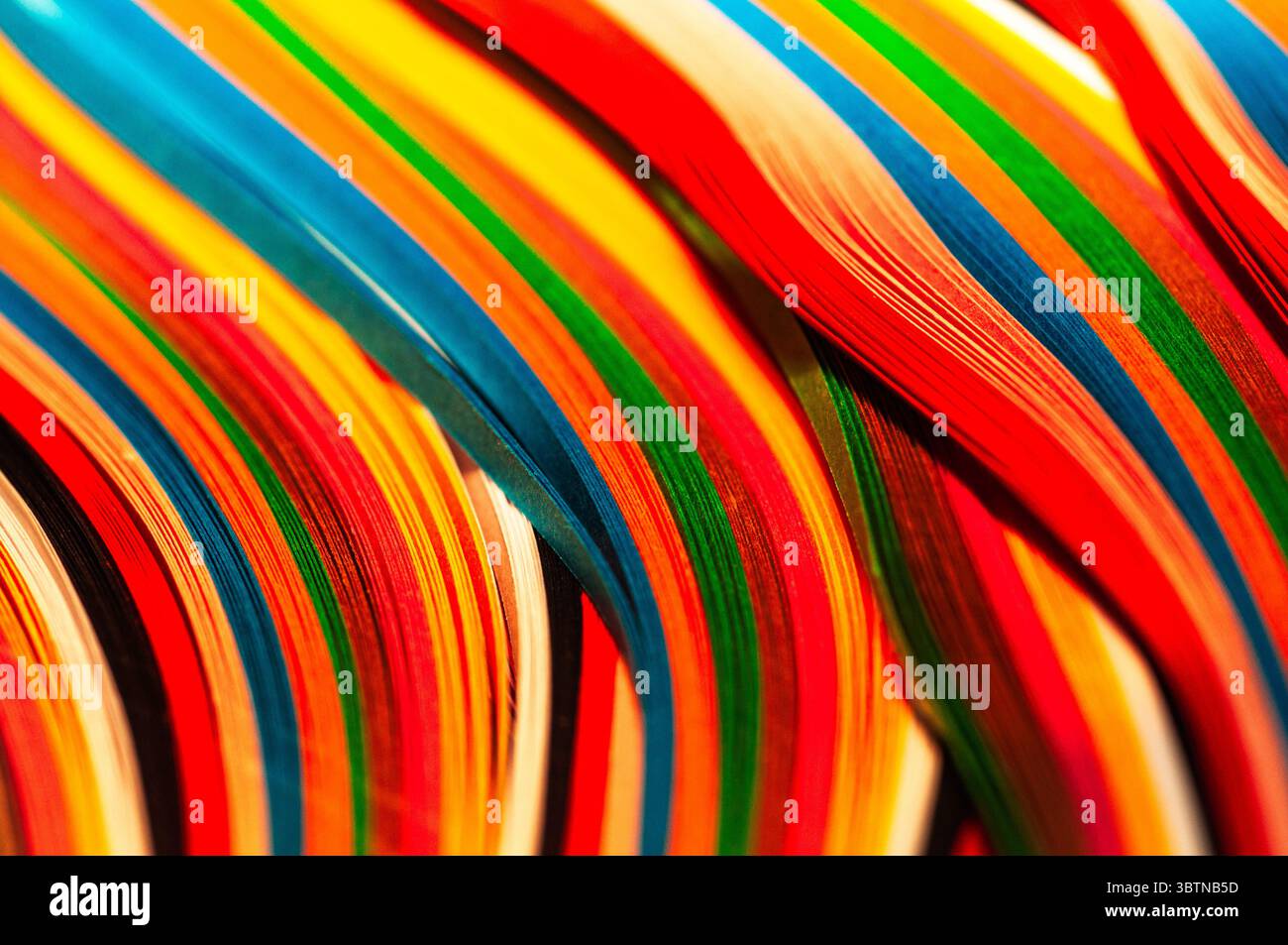 Eine lebendige Nahaufnahme von mehrfarbigen Streifen in fließenden Wellen. Perfekt für abstrakte Hintergründe, kreatives Design oder handwerkliches und farbiges Material Stockfoto
