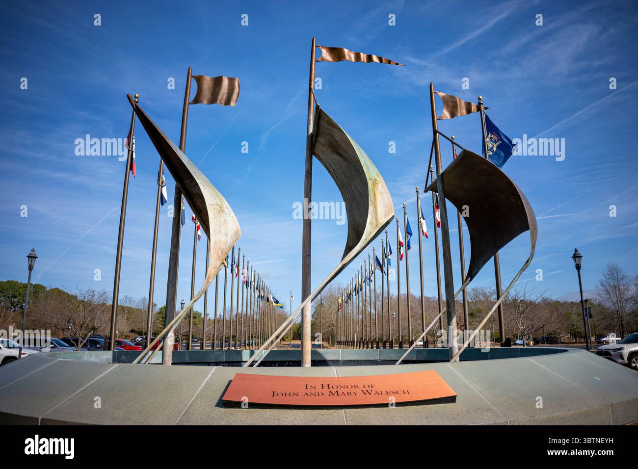 Jamestown Settlement Ship Sail Sculpture at Historic Site Entrance in Virginia // JAMESTOWN, Virginia — die Schiffssegelskulptur am Eingang zu Jamestown Settlement zeigt abstrakte Metallsegelformen, die die drei Schiffe darstellen, die englische Kolonisten 1607 nach Virginia brachten. Die Susan Constant, Godspeed und Discovery verließen London im Dezember 1606 und erreichten Jamestown im folgenden Jahr und gründeten die erste dauerhafte englische Siedlung in Nordamerika. Die moderne Kunstinstallation besteht aus segelähnlichen Metallkonstruktionen, die auf Pfählen montiert sind und die Seefahrt evozieren Stockfoto