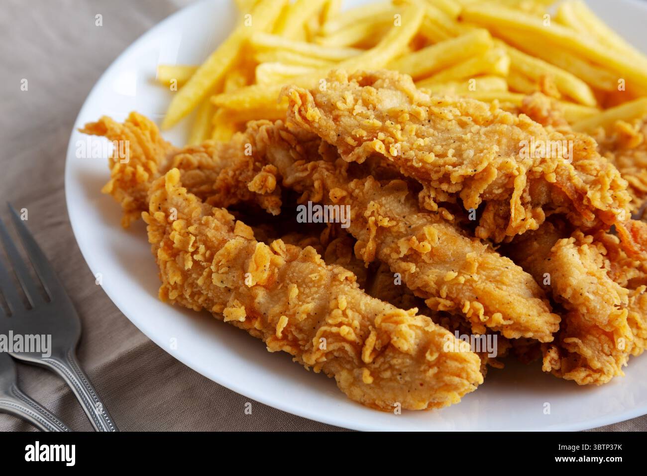 Hausgemachte Hähnchenstreifen mit Pommes frites auf einem Teller, Blick aus einem niedrigen Winkel. Nahaufnahme. Stockfoto