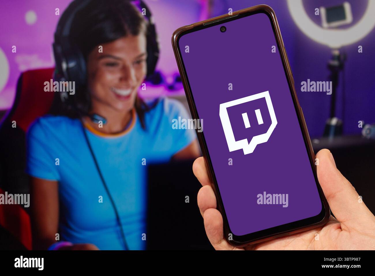 Eine männliche Hand, die ein Smartphone mit der rechten Hand hält, mit Twitch-Video-Live-Streaming-Service-Logo und einer verschwommenen St Stockfoto