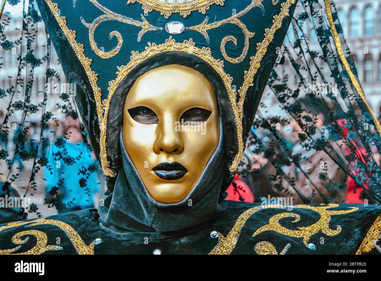 Nahaufnahme einer Person, die beim Karneval von Venedig eine aufwendige goldene Maske und ein kunstvolles schwarz-goldenes Kostüm trägt. Stockfoto