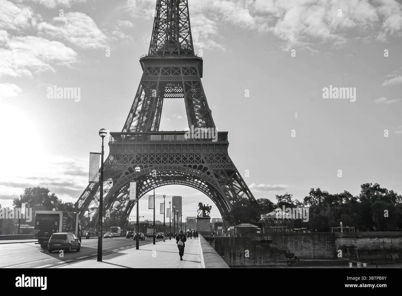 Schwarzweißfoto des Eiffelturms von der Straße mit Menschen und Autos. Stockfoto