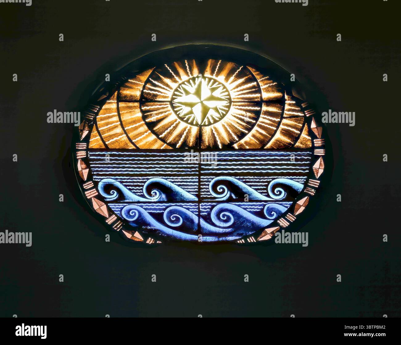 Buntglasfenster mit einer stilisierten Sonne über den Meereswellen, mit geometrischen und symbolischen Mustern, die in warmen und kühlen Tönen leuchten. Stockfoto