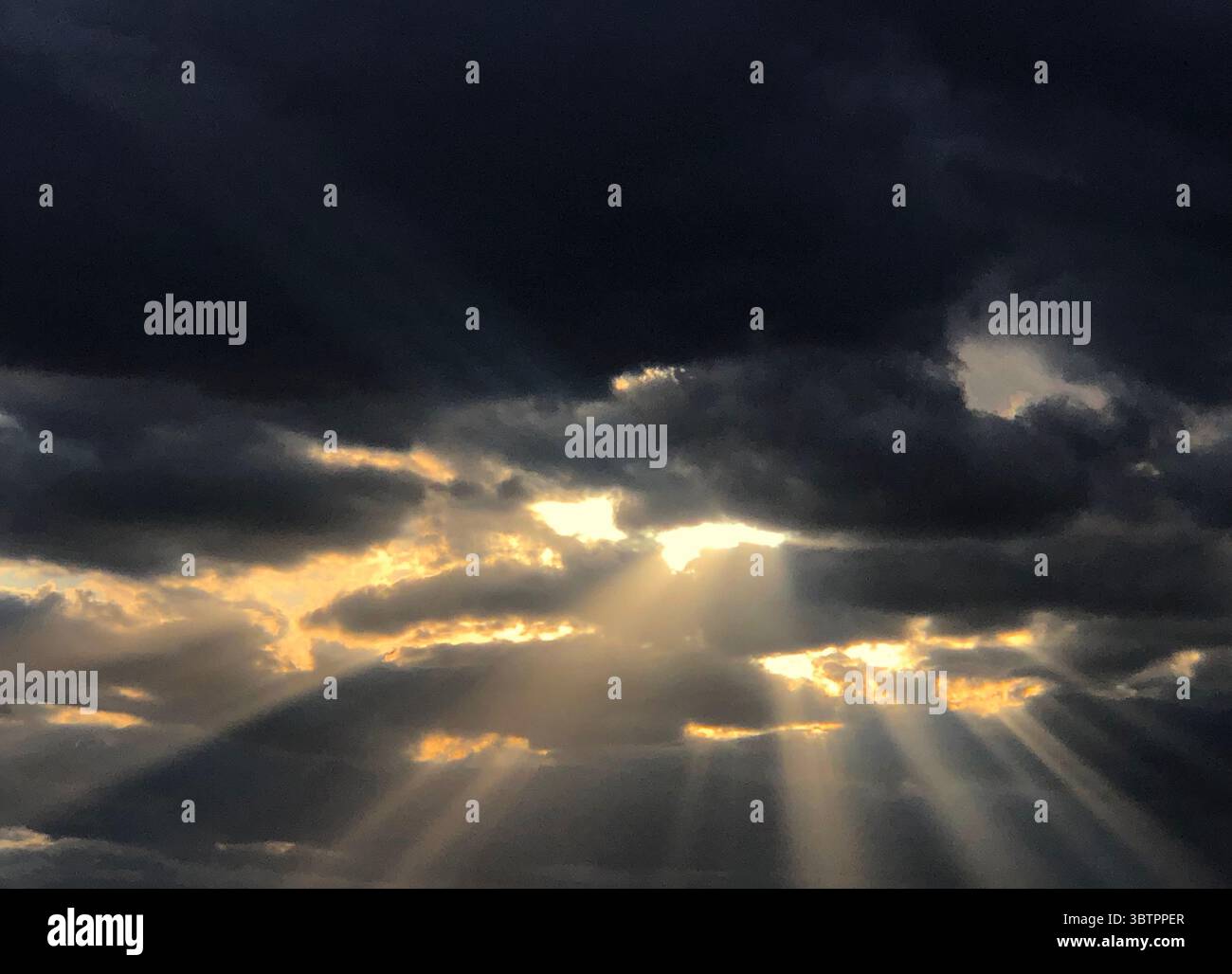Sonnenstrahlen leuchten durch die Wolken eines Sturms Stockfoto