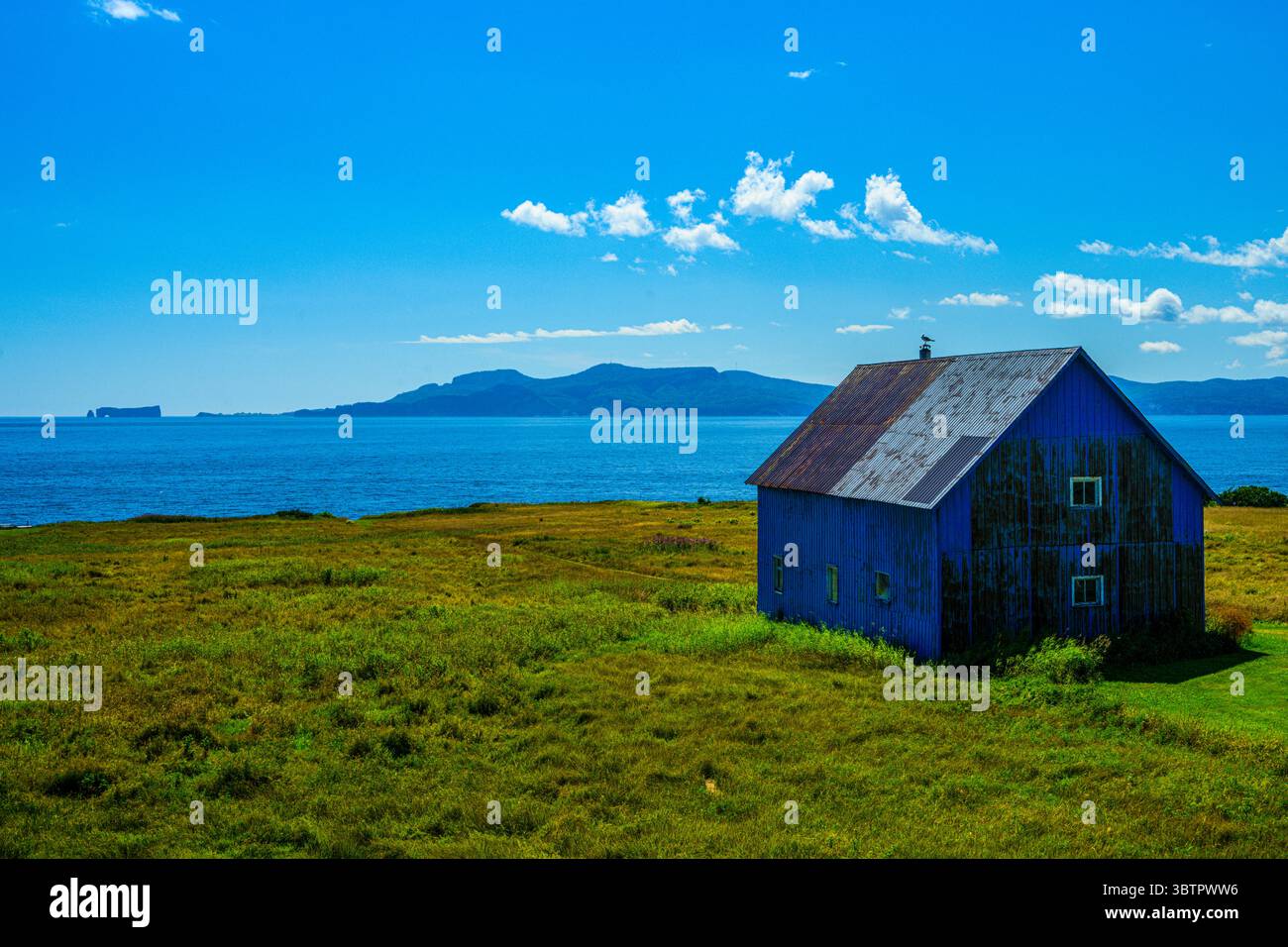 Blaues Gebäude, Baie de Malbaieund entfernter Rocher Percé (Rock), Gaspe, Belle Anse, Quebec QC, Kanada Stockfoto