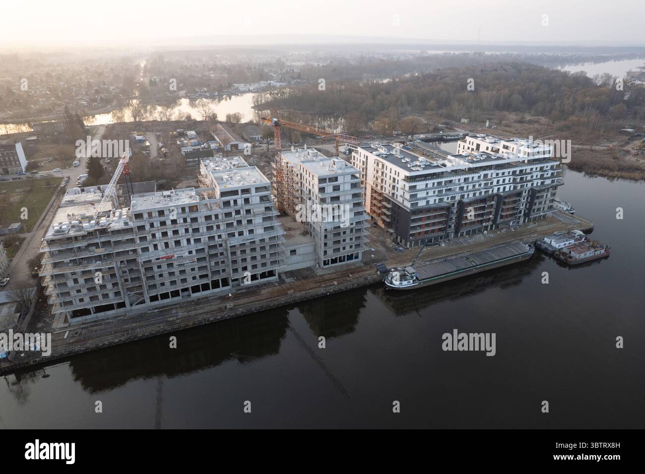 Drohnenansicht einer großangelegten Immobilienentwicklung am Uferufer. Die Website zeigt moderne mehrstöckige Wohngebäude in verschiedenen Phasen Stockfoto