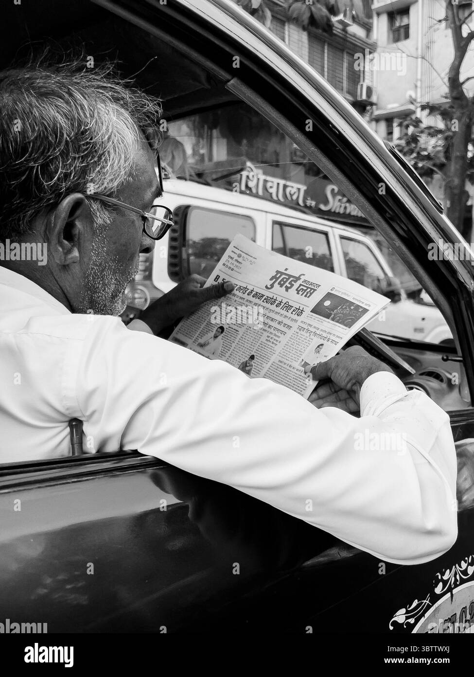 Ein Mann liest eine Zeitung in einem lokalen Taxifahrer in einer belebten Straße in mumbai indien Stockfoto