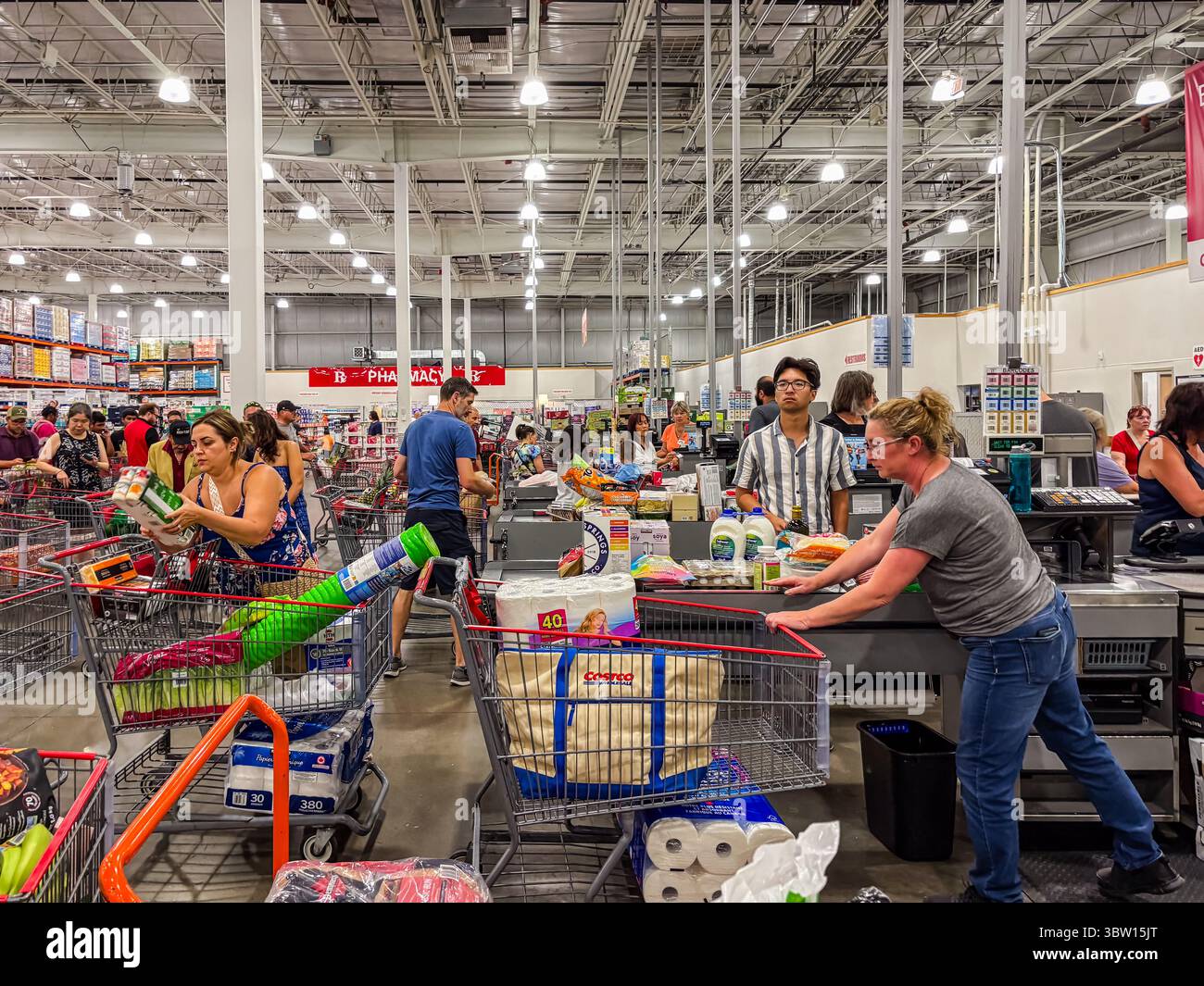Innenansicht des Costco-Lagers von Kunden, die aus- und Einkäufe tätigen, mit vollen Wagen und Massenartikeln in einer geschäftigen Einzelhandelsumgebung. Stockfoto