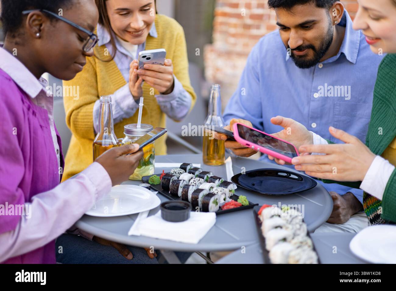 Freunde, die Sushi und Telefone teilen Stockfoto