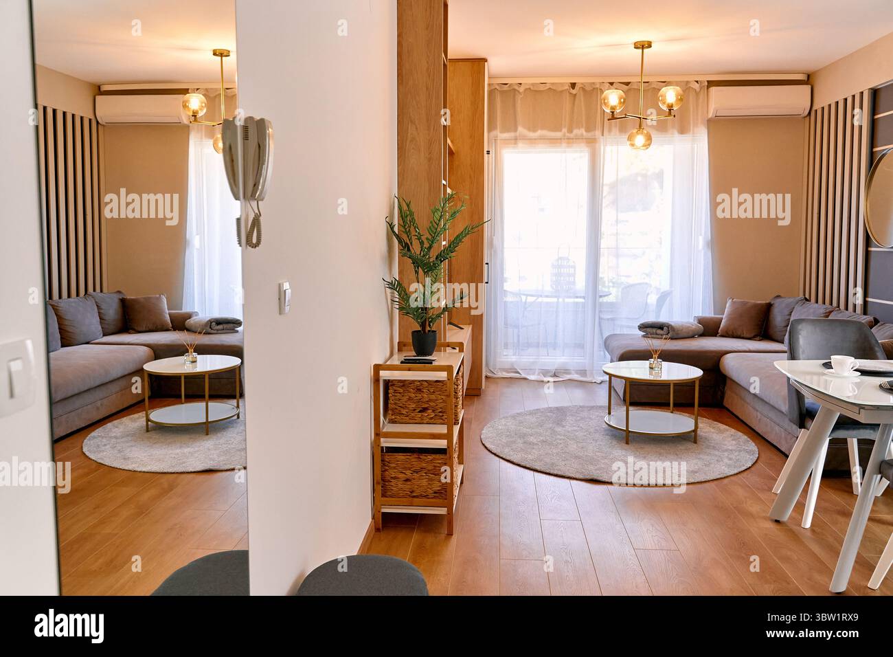 Ein stilvolles, modernes Wohnzimmer mit eleganten Möbeln, warmer Beleuchtung und entspannender Einrichtung, die ein gemütliches und symmetrisches Layout mit Verachtung hervorhebt Stockfoto