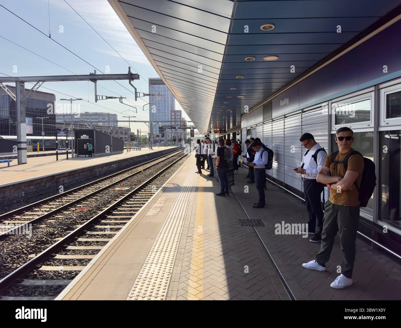Juli 2025 Bahnpassagiere warten am Bahnhof Reading in Berkshire auf den frühen Morgenzug nach London Paddington, an einem sonnigen Morgen Stockfoto