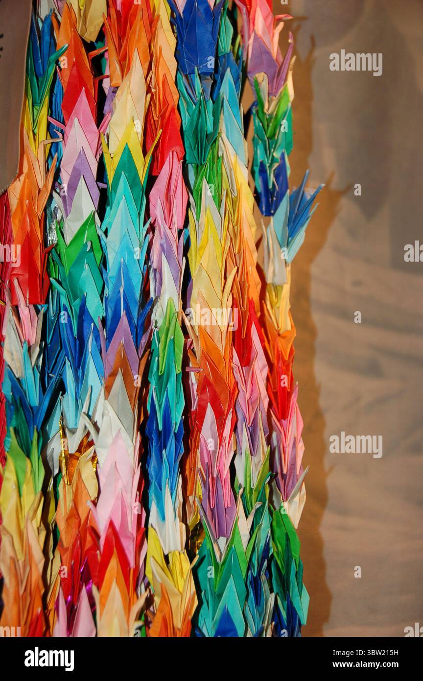 Bunte Papierkraniche, die in einer Senbazuru aneinandergereiht sind, ein traditionelles japanisches Symbol für Frieden, Hoffnung und Heilung durch die Kunst des Origami Stockfoto