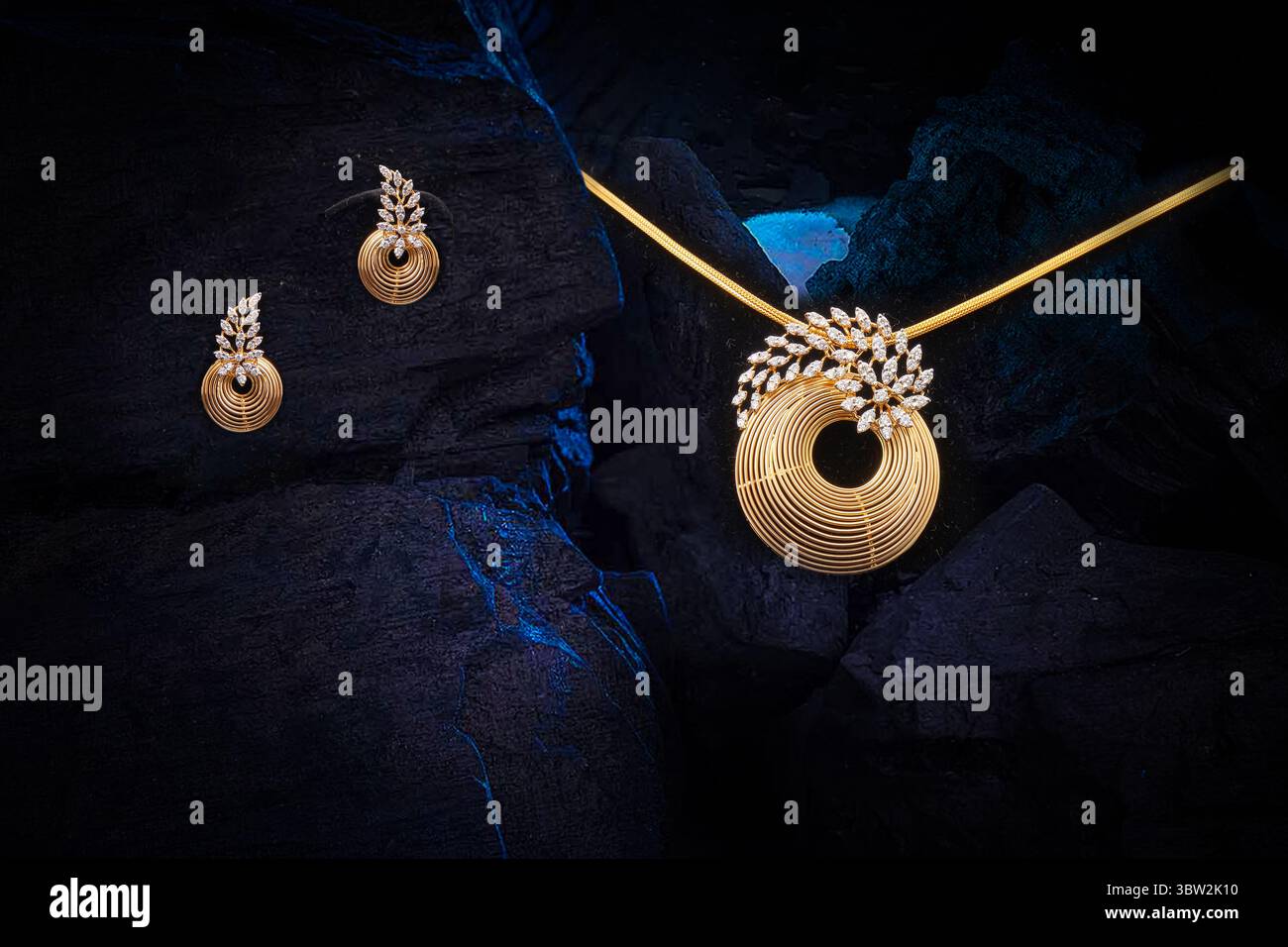 Eine atemberaubende goldene Halskette mit einem einzigartigen Spiralanhänger, der mit Diamanten und passenden Ohrringen verziert ist und kunstvoll auf einem dramatischen dunklen, felsigen B abgebildet wird Stockfoto