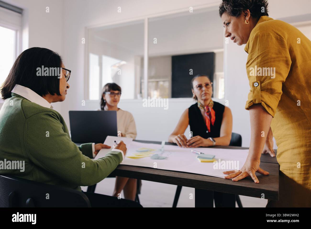 Ein Team von Fachleuten, die an einem Brainstorming-Meeting in einem modernen Arbeitsbereich teilnahmen. Sie verwenden Notizen und Tools, um zusammenzuarbeiten und Ideen auszutauschen Stockfoto