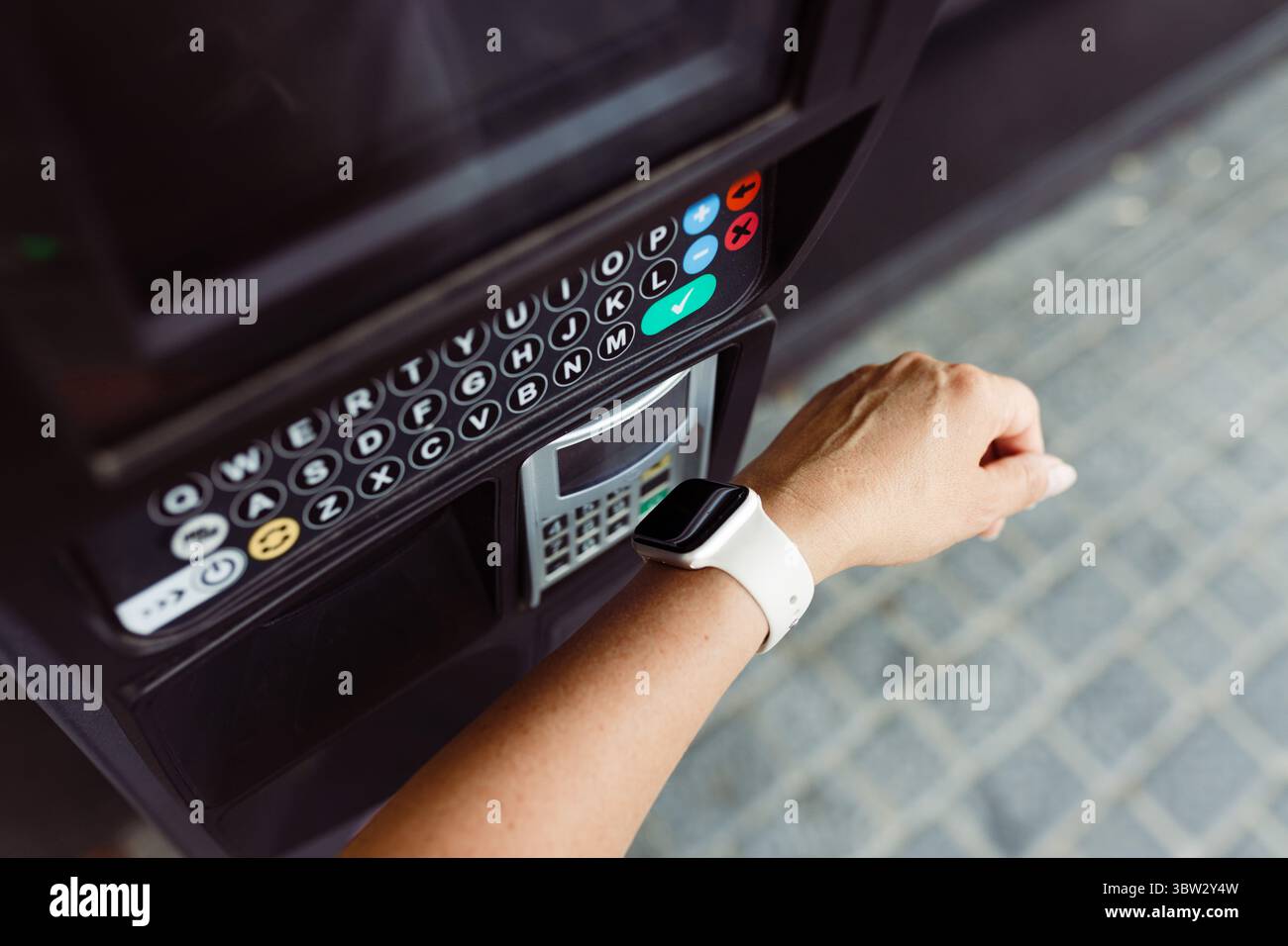 Person, die kontaktlos mit Smart Watch bezahlt, um Parkgebühren zu bezahlen. Kostenpflichtig am Parkautomaten. Kunden, die eine schnelle und einfache kontaktlose Zahlung tätigen Stockfoto