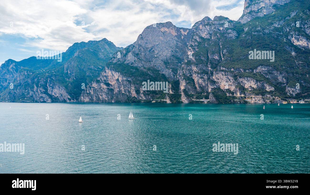 Torbole, Gardasee, Italien - 15. Juli 2025: Weitläufiger Blick über den Gardasee in Norditalien - der größte See des Landes ist von steilen Berghängen und türkisfarbenem Wasser umgeben. *** Weitläufige Drohnenansicht über den Gardasee in Norditalien der größten See des Landes zeigt sich umgeben von steilen Berghängen, türkisfarbenem Wasser. Stockfoto