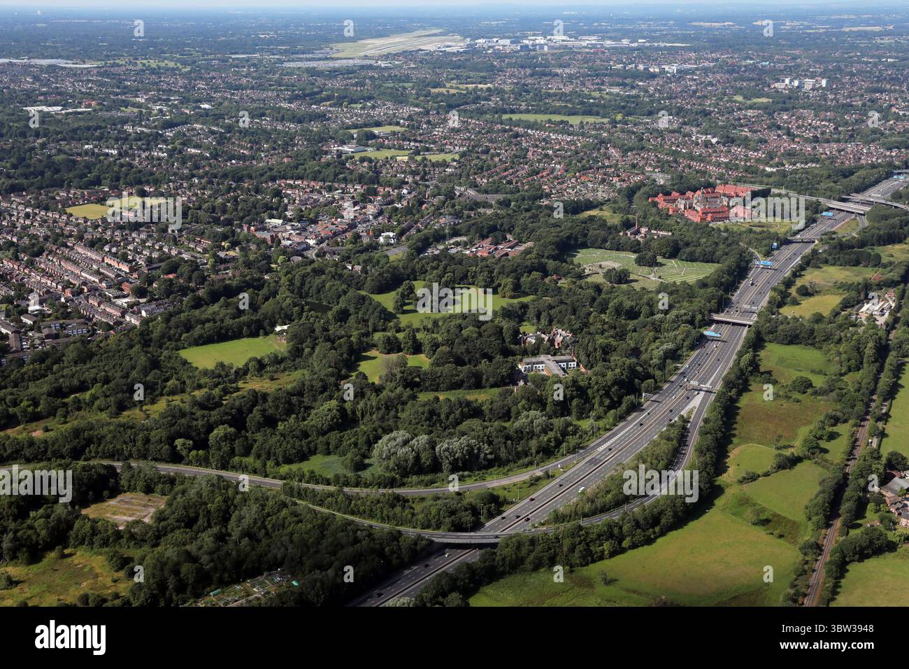 Aus der Vogelperspektive in Richtung Westen in Richtung Manchester Airport auf der Autobahn M60 an der Anschlussstelle 2 in der Nähe von Cheadle, Manchester Stockfoto