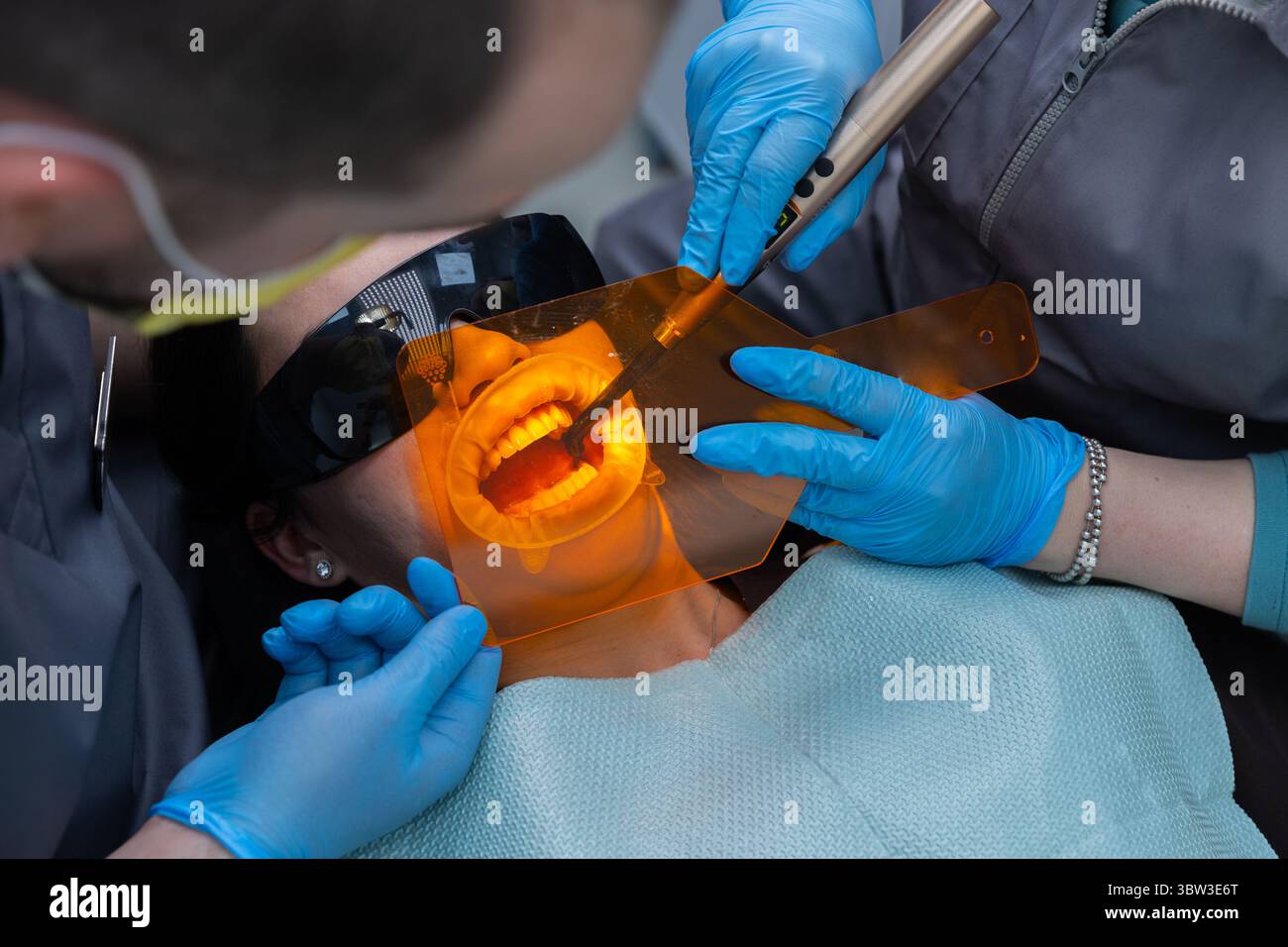 Ein zahnärztlicher Eingriff in der Praxis: Ein Patient, der mit Spezialwerkzeugen und Schutzausrüstung versorgt wird in einer modernen Zahnklinik Stockfoto