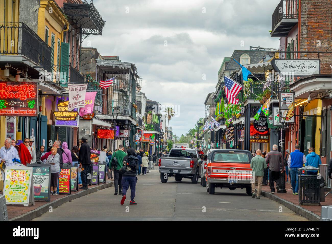 Touristen und Musikclubs und Restaurantneonschilder im berühmten Bourbon im French Quarter, New Orleans, Louisiana Stockfoto