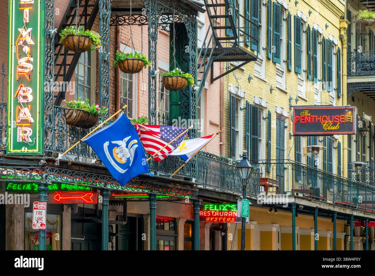 Flaggen, Musikklubs und Restaurantneonschilder in einer Straße im French Quarter, New Orleans, Louisiana Stockfoto