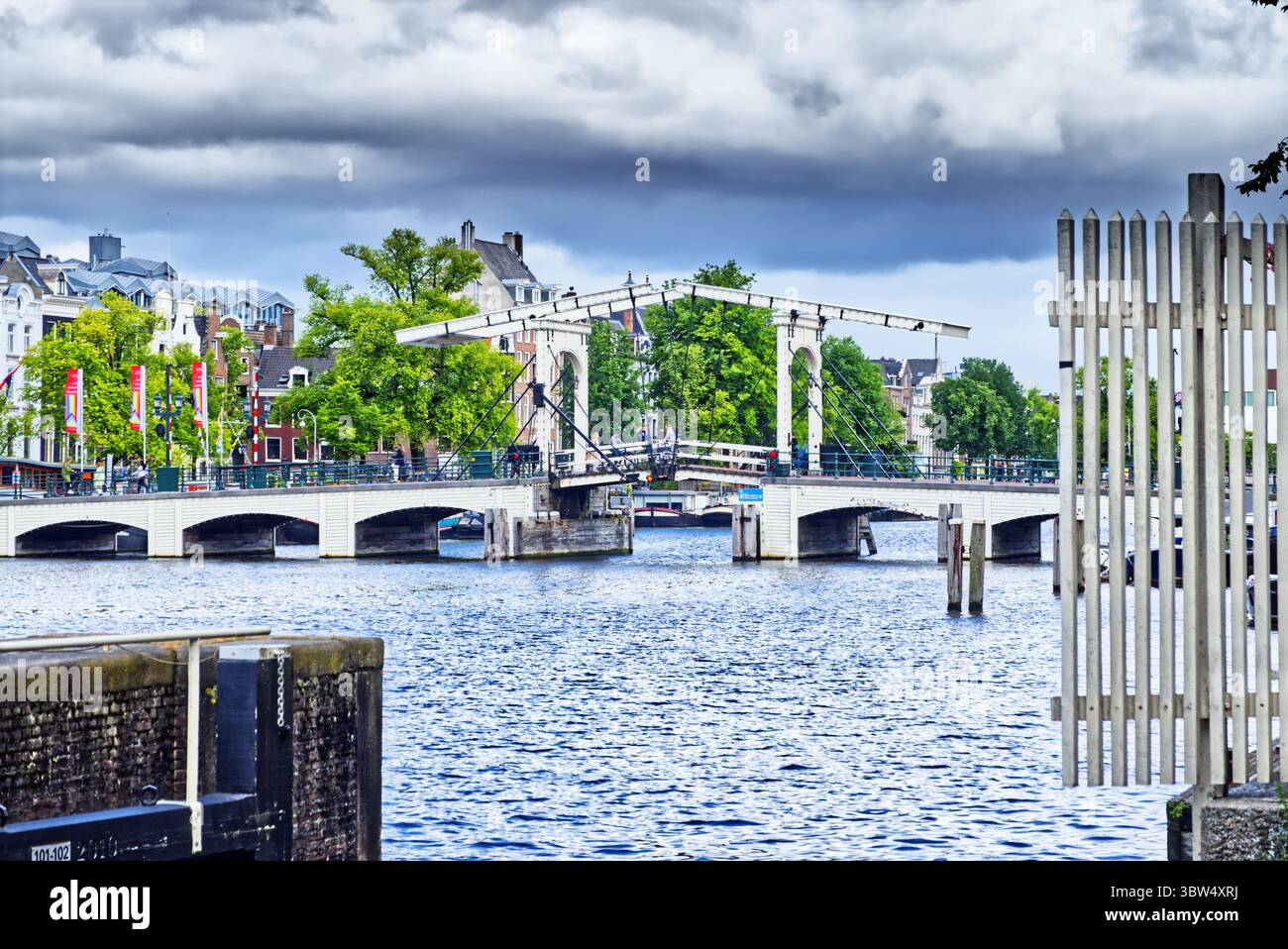 Die magere brug, eine traditionelle weiße Zugbrücke, erhebt ihre Bascules über die amstel in amsterdam, niederlande, unter bewölktem Himmel Stockfoto