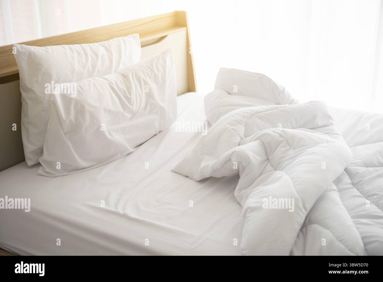Weiß ungemachten Bett am Morgen mit Sonnenschein mit weißen Vorhang Hintergrund in eleganten Haus. Interior Design und luxuriöse Möbel Konzept. Drinnen lif Stockfoto