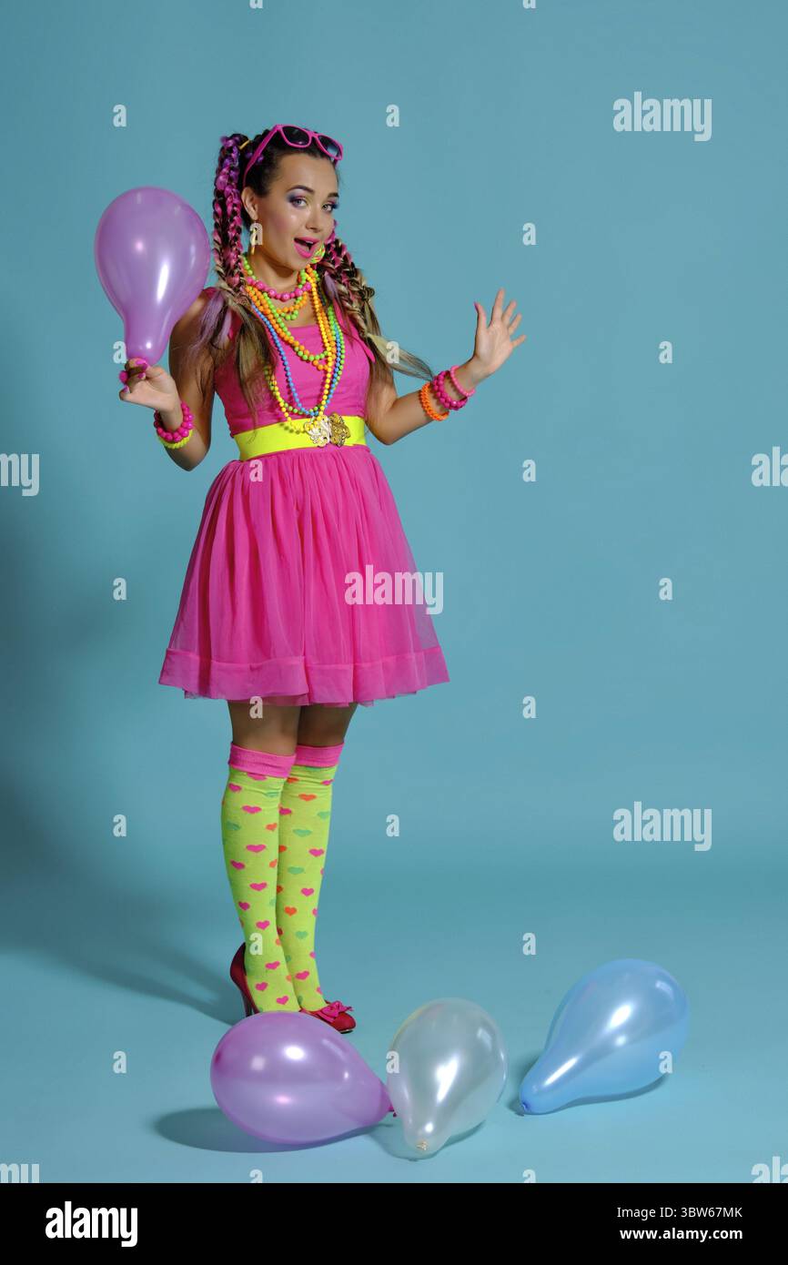 Volle Länge Foto von einer sympathischen Frau in Sonnenbrille auf dem Kopf, mit einem bunten Zöpfe Frisur und Make-up, mit Luftballons posing Stockfoto