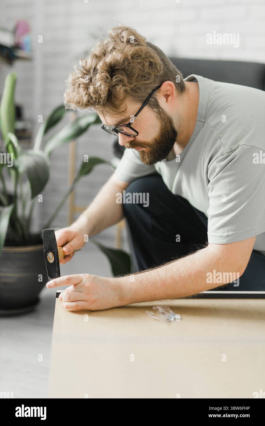 Junger attraktiver Mann baut Möbel - handwerker und Inneneinrichtung Konzept Stockfoto