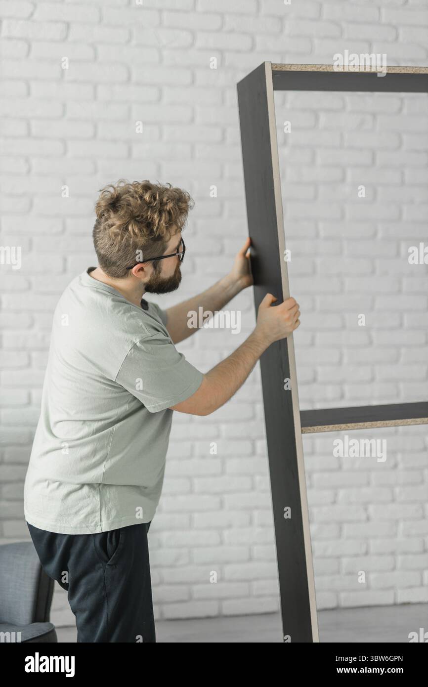 Junger attraktiver Mann baut Möbel - handwerker und Inneneinrichtung Konzept Stockfoto