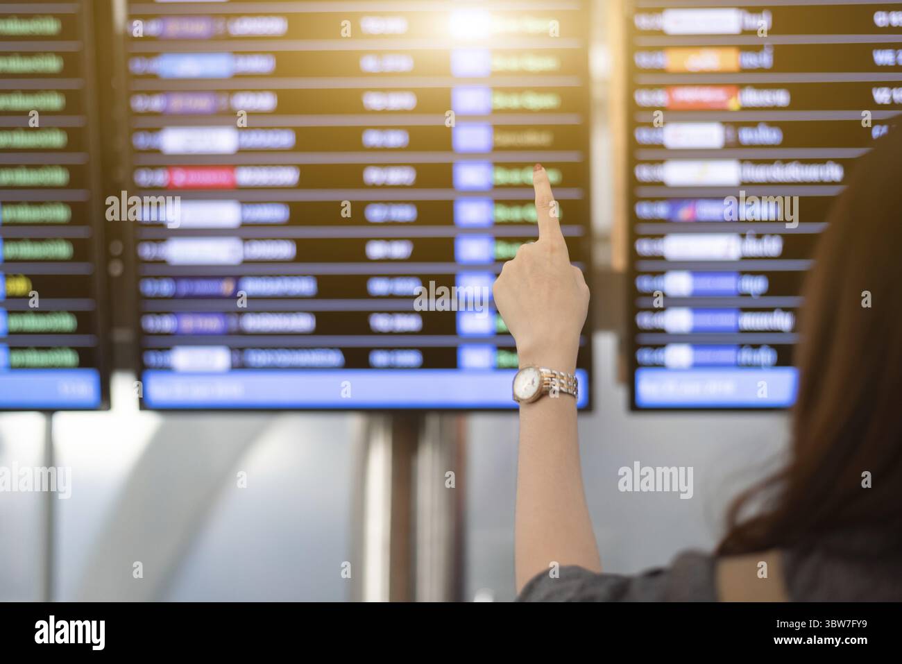 Rückansicht der Frau auf der Suche nach Flügen von Flugplan im Flughafen. Weibliche Touristen Zeit Tabelle zeigt für das Flugzeug. Reisen und Transport Stockfoto