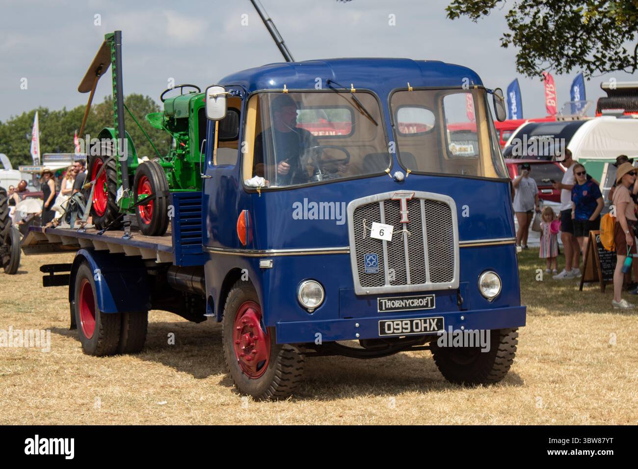 Ein Mann, der an einem sonnigen Tag in England einen hölzernen croft-Pritschenwagen mit einem John Deere-Traktor fährt. Stockfoto