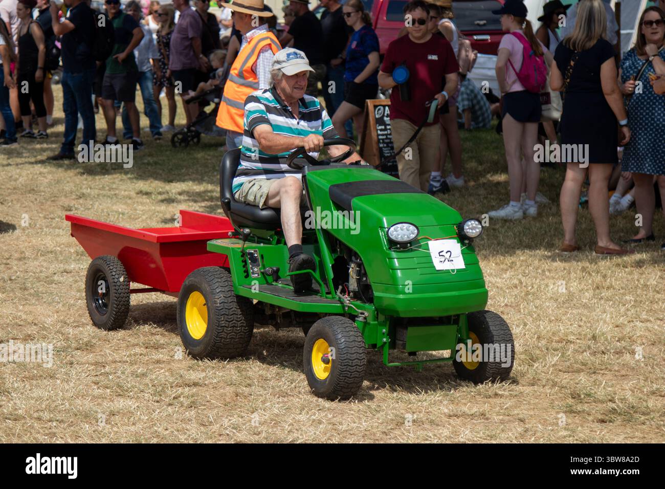 Eine Frau, die einen grün-gelben Rasenmäher fährt Stockfoto