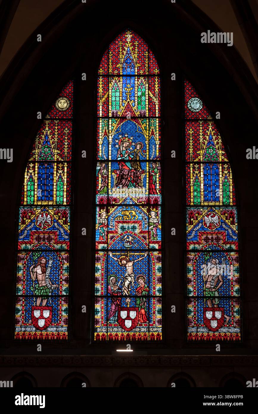 Jungfrau mit Kind und die Kreuzigung im Buntglasfenster aus der Zeit um 1320 im Freiburger Münster-Innenraum in Freiburg im Breisgau. Stockfoto