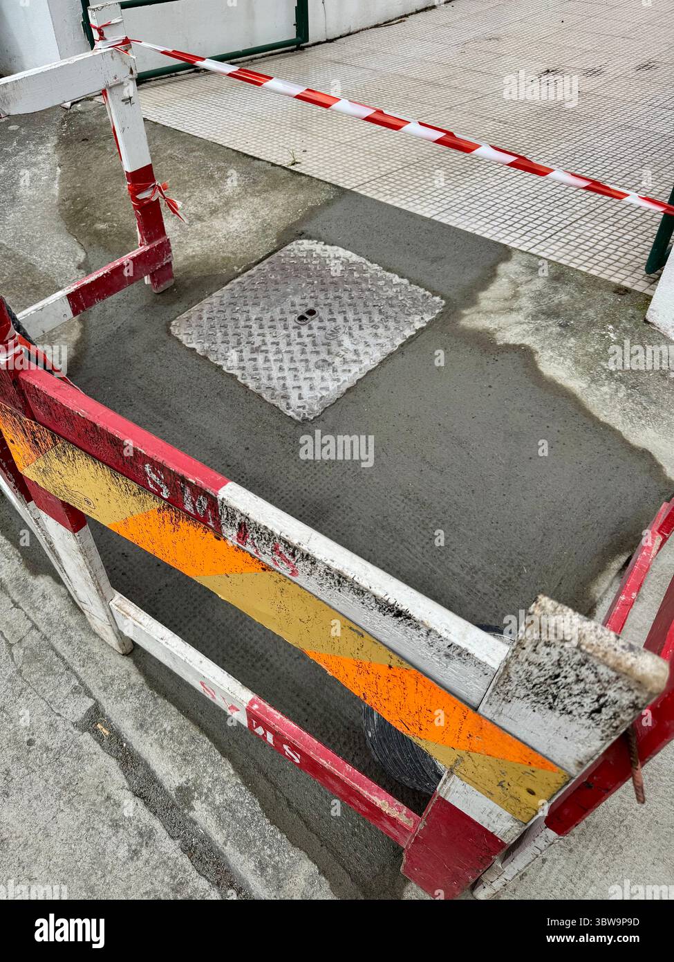 Frisch gegossener Beton um eine Mannlochabdeckung auf einer städtischen Baustelle - Smartphone-aufgenommenes Stockfoto