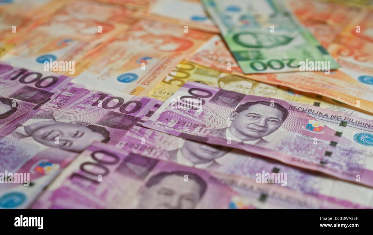 Die philippinischen Banknoten sind verstreut und weisen verschiedene Stückelungen auf, darunter 100-Peso- und 200-Peso-Scheine. Stockfoto
